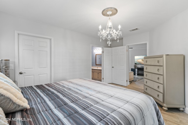 bedroom with ensuite bath, sink, a chandelier, and light wood-type flooring