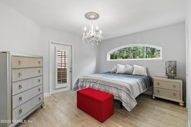 bedroom featuring access to exterior, light hardwood / wood-style floors, and a chandelier