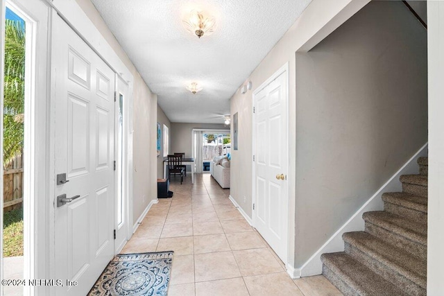 tiled entryway with ceiling fan and a textured ceiling