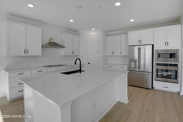 kitchen featuring white cabinetry, sink, stainless steel appliances, light hardwood / wood-style flooring, and a kitchen island with sink