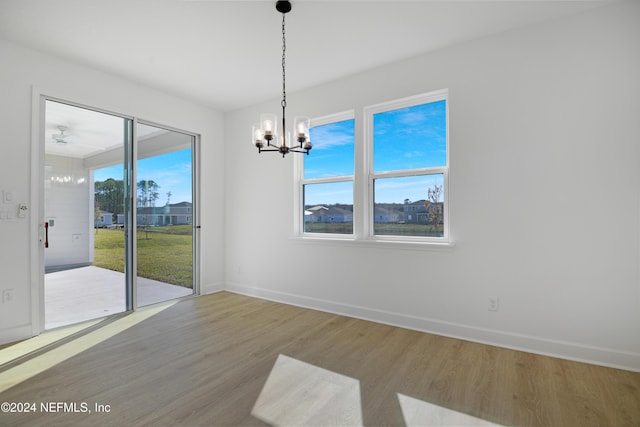 unfurnished dining area featuring plenty of natural light, hardwood / wood-style floors, and an inviting chandelier