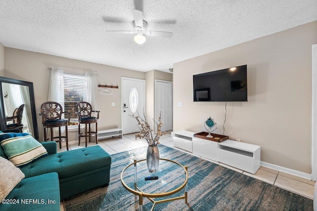 living room featuring ceiling fan, light tile patterned flooring, and a textured ceiling