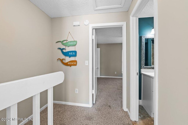 hall featuring carpet flooring and a textured ceiling