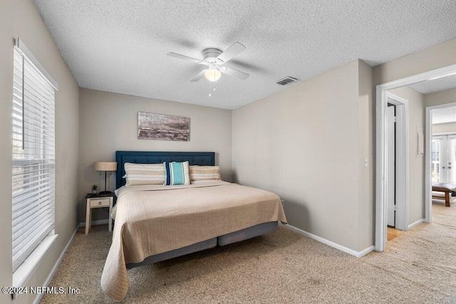 bedroom with a textured ceiling, light colored carpet, and ceiling fan