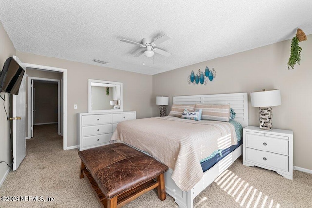 carpeted bedroom with ceiling fan and a textured ceiling