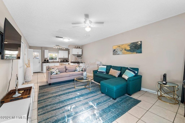 living room with ceiling fan, light tile patterned floors, and a textured ceiling