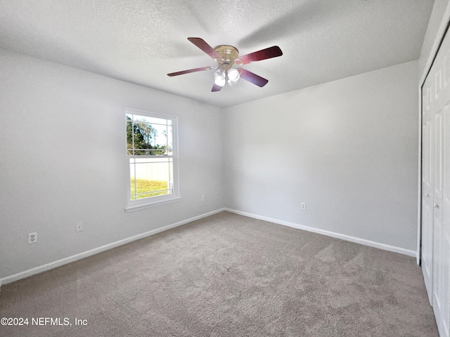 carpeted empty room featuring ceiling fan and a textured ceiling