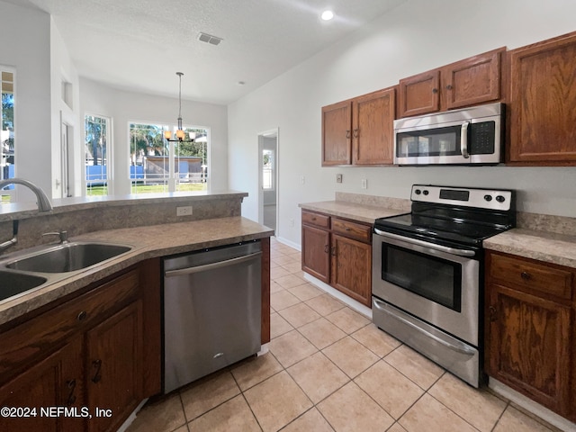 kitchen featuring sink, decorative light fixtures, appliances with stainless steel finishes, a notable chandelier, and light tile patterned flooring