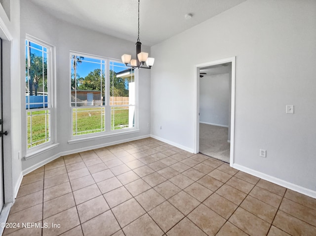 unfurnished dining area with light tile patterned floors, an inviting chandelier, and plenty of natural light