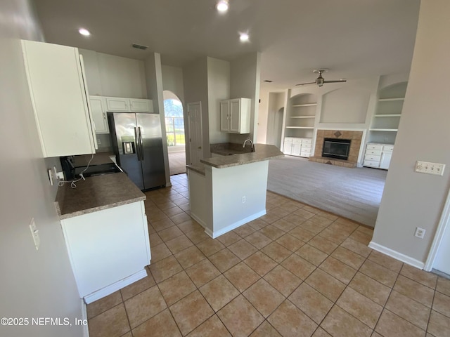 9767 Brockham Ct, Jacksonville, FL 32221 - kitchen with stainless steel fridge with ice dispenser, a tile fireplace, ceiling fan, light tile patterned flooring, and white cabinets