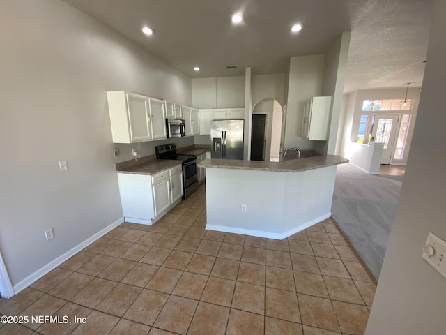 9767 Brockham Ct, Jacksonville, FL 32221 - kitchen with appliances with stainless steel finishes, white cabinetry, baseboards, light tile patterned floors, and a peninsula