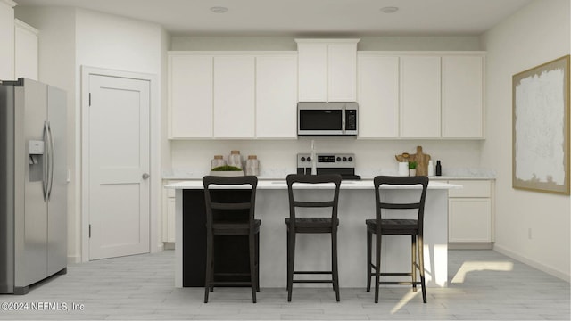 kitchen featuring an island with sink, a breakfast bar area, white cabinets, stainless steel appliances, and light hardwood / wood-style flooring