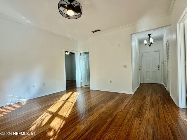 unfurnished room with hardwood / wood-style floors, an inviting chandelier, and crown molding