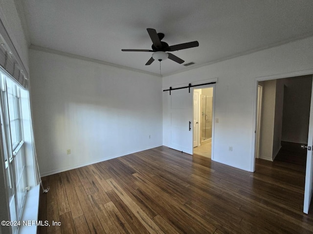 spare room with ceiling fan, a barn door, dark hardwood / wood-style floors, a textured ceiling, and ornamental molding