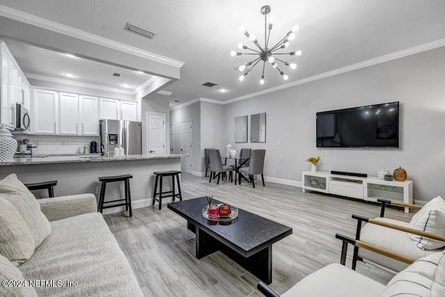 living room featuring crown molding, light wood-type flooring, and an inviting chandelier