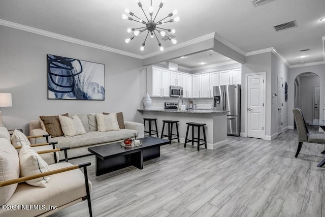 living room with a chandelier, light hardwood / wood-style floors, and ornamental molding