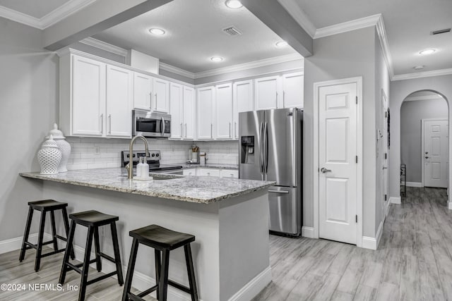 kitchen featuring light stone counters, white cabinetry, crown molding, and appliances with stainless steel finishes