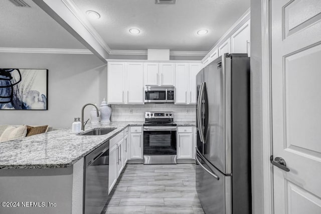 kitchen with light stone countertops, sink, stainless steel appliances, kitchen peninsula, and white cabinets