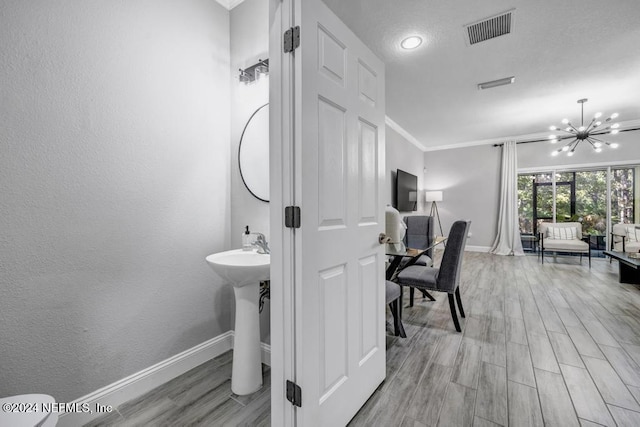 bathroom featuring hardwood / wood-style floors, ornamental molding, and an inviting chandelier