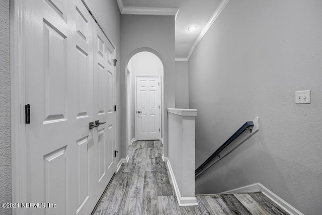 corridor with ornamental molding and light hardwood / wood-style flooring