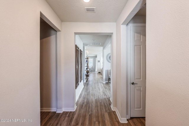 hallway featuring a textured ceiling and dark hardwood / wood-style flooring