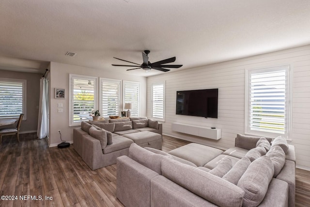 living room with ceiling fan, dark wood-type flooring, and a wealth of natural light