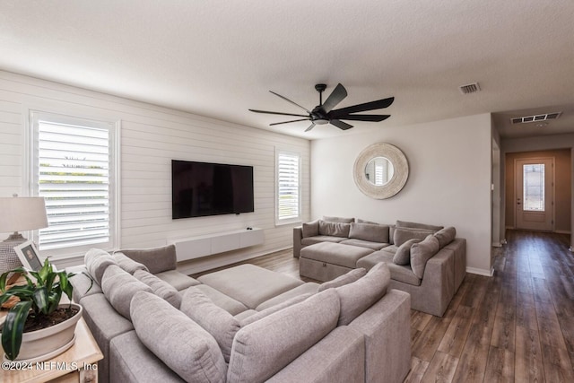 living room with a wealth of natural light, dark hardwood / wood-style flooring, ceiling fan, and a textured ceiling