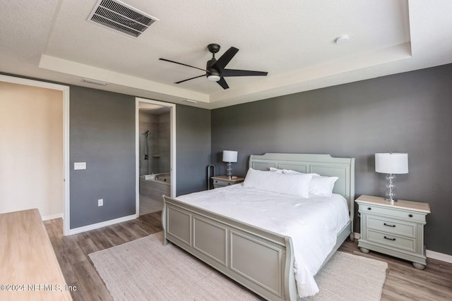 bedroom featuring ensuite bathroom, ceiling fan, a textured ceiling, and light hardwood / wood-style flooring