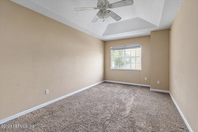 carpeted empty room featuring ceiling fan, a raised ceiling, and a textured ceiling