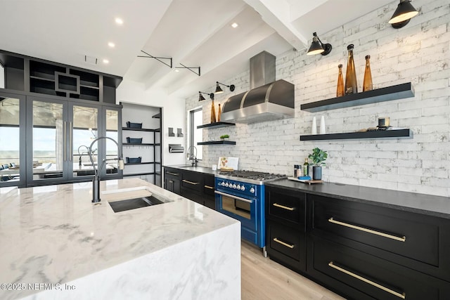 1304 Strand St, Neptune Beach, FL 32266 - kitchen featuring open shelves, wall chimney range hood, range with two ovens, dark cabinets, and a sink
