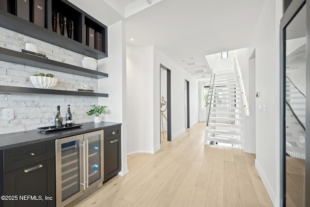 1304 Strand St, Neptune Beach, FL 32266 - indoor dry bar with wine cooler, stairway, tasteful backsplash, light wood finished floors, and baseboards