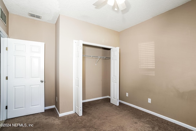 unfurnished bedroom featuring dark colored carpet, a textured ceiling, a closet, and ceiling fan