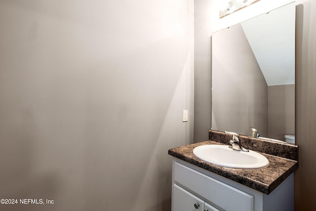 bathroom featuring vanity, toilet, and lofted ceiling