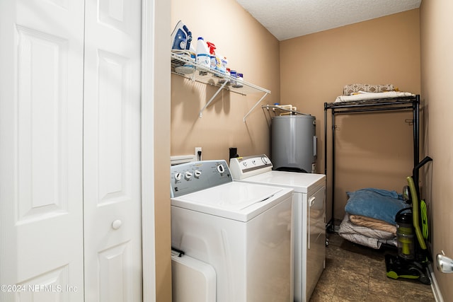 laundry area with washing machine and clothes dryer, a textured ceiling, and water heater