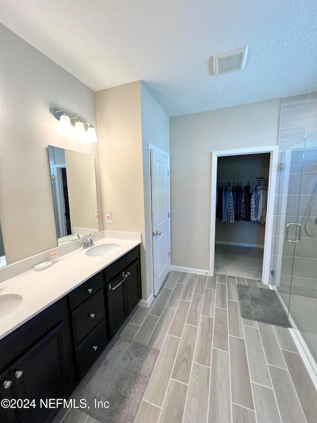 bathroom with vanity, an enclosed shower, and a textured ceiling