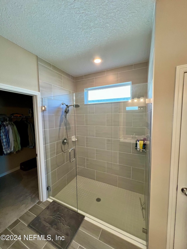 bathroom with wood-type flooring, a textured ceiling, and a shower with shower door