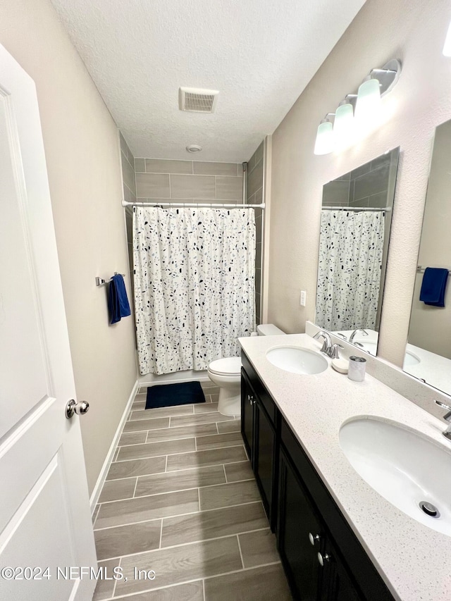 bathroom with vanity, a textured ceiling, toilet, and curtained shower