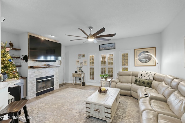 living room with a fireplace, light hardwood / wood-style floors, and ceiling fan