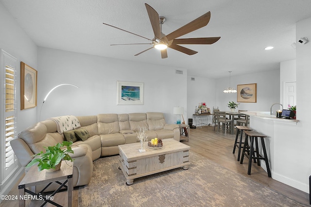 living room with dark hardwood / wood-style floors and ceiling fan with notable chandelier