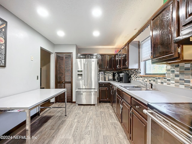 kitchen with light wood-type flooring, stainless steel fridge with ice dispenser, dark brown cabinetry, and sink