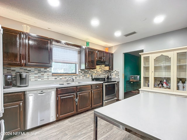 kitchen featuring dark brown cabinetry, sink, stainless steel appliances, light hardwood / wood-style flooring, and backsplash