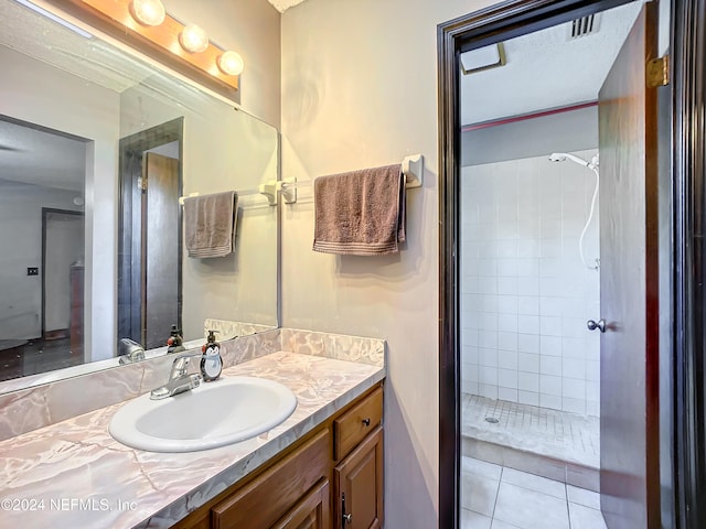 bathroom with tile patterned floors, vanity, and a tile shower