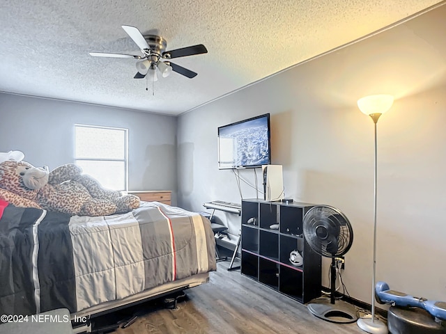 bedroom with ceiling fan, wood-type flooring, and a textured ceiling