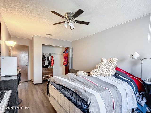 bedroom featuring ceiling fan, a closet, wood-type flooring, and a textured ceiling