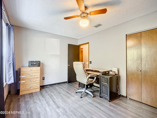 home office with ceiling fan, light hardwood / wood-style floors, and a textured ceiling