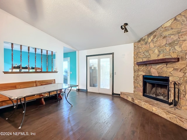 interior space featuring dark hardwood / wood-style floors, a stone fireplace, lofted ceiling, and a textured ceiling