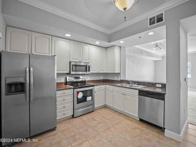 kitchen with white cabinets, sink, dark stone countertops, ornamental molding, and stainless steel appliances