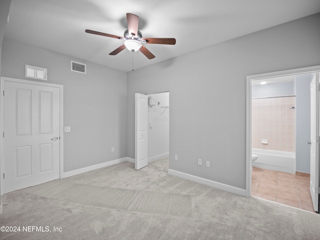 unfurnished bedroom with connected bathroom, ceiling fan, a spacious closet, light colored carpet, and a closet