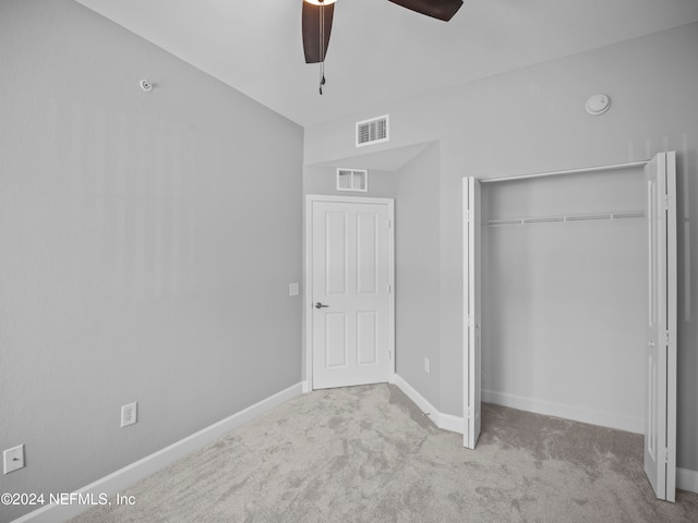 unfurnished bedroom with ceiling fan, light colored carpet, and a closet