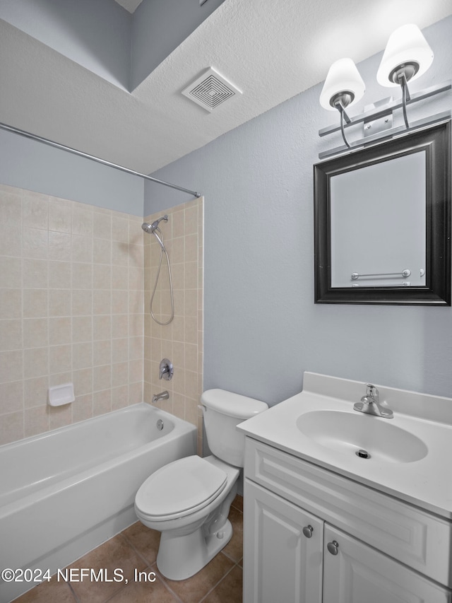 full bathroom featuring a textured ceiling, vanity, tile patterned flooring, toilet, and tiled shower / bath